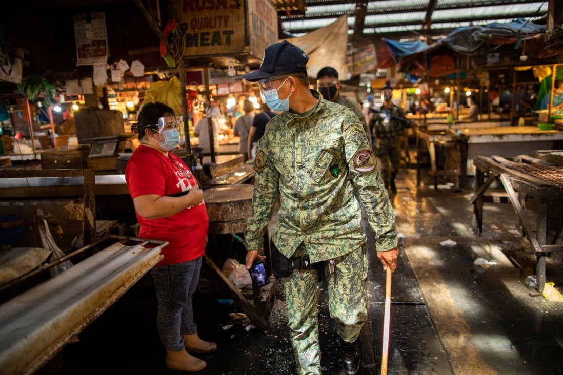 An armed police officer patrols a public market in the Philippines where wearing face masks and face shields is mandatory amid the pandemic. Photo: Reuters