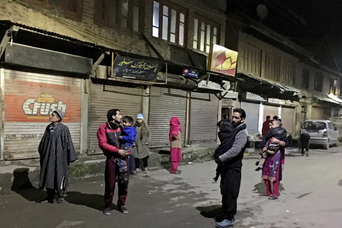 Residents carrying their children stand on a road after vacating their houses following an earthquake in Srinagar, India on Friday. Photo: Reuters