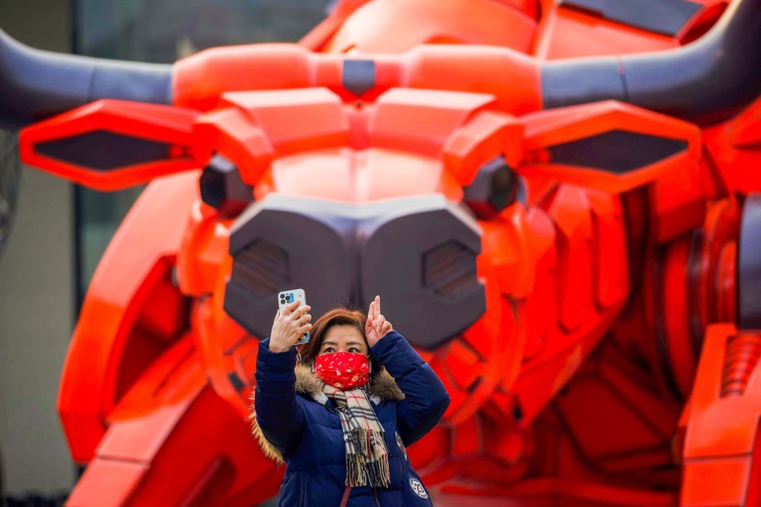 A woman takes a selfie in front of a bull sculpture at a mall in Beijing. Hong Kong stocks rose on the first trading day of the Lunar New Year on Tuesday. Photo: AFP