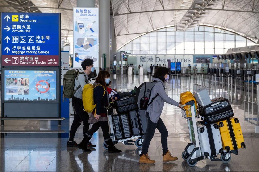 Travellers wearing protective masks push luggage carts through the departures hall at Hong Kong International Airport. Photo: Bloomberg