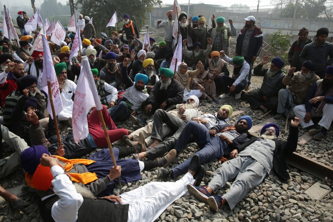 Farmers shout slogans as they lay across rail lines on the outskirts of Amritsar on Thursday as part of a four-hour train blockade protest against India’s agricultural reforms. Photo: EPA