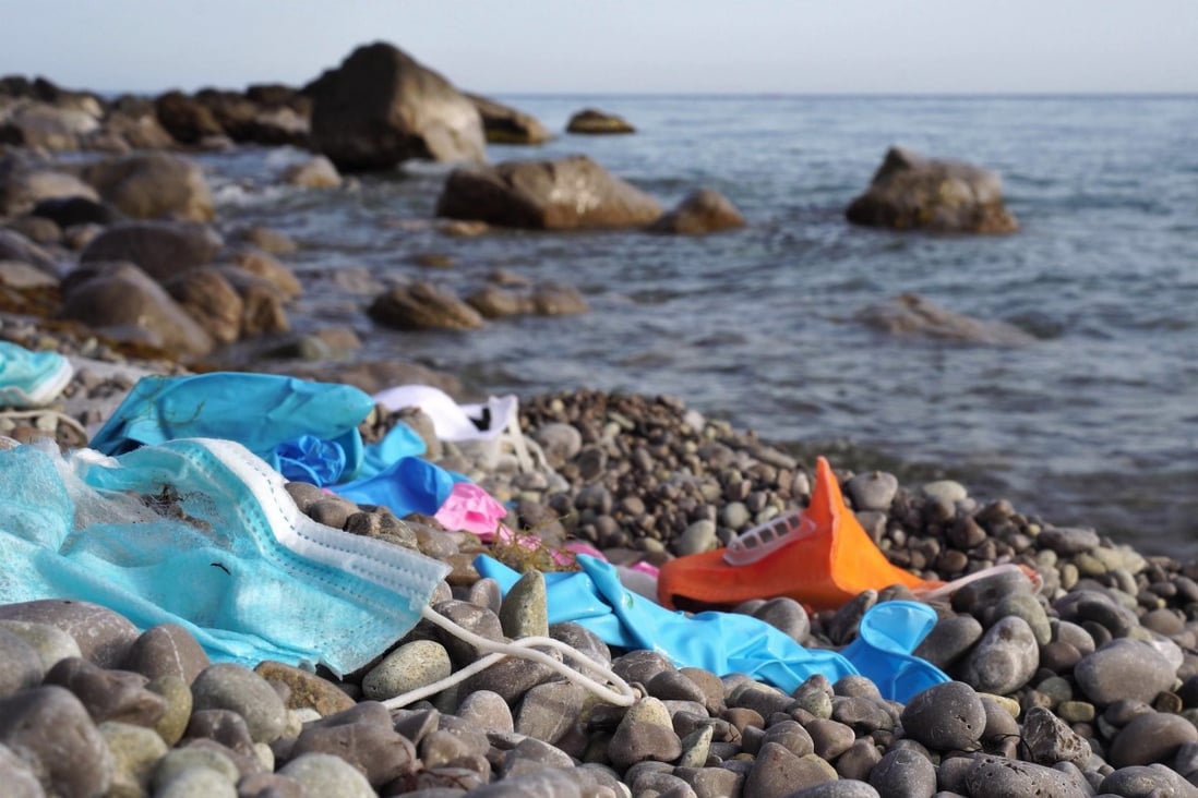 Single-use masks and used latex gloves litter a beach. Photo: Shutterstock