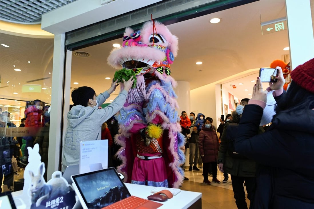 A man makes an offering as a lion dance team perform inside a mall in Beijing on Tuesday, on the fifth day of the Lunar New Year. Photo: AFP