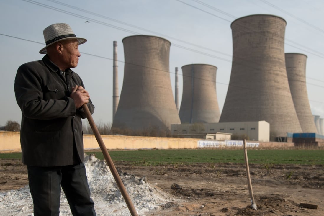 A man looks towards chimney stacks in a field outside a power plant in Xingtai, southern Hebei province. Photo: AFP