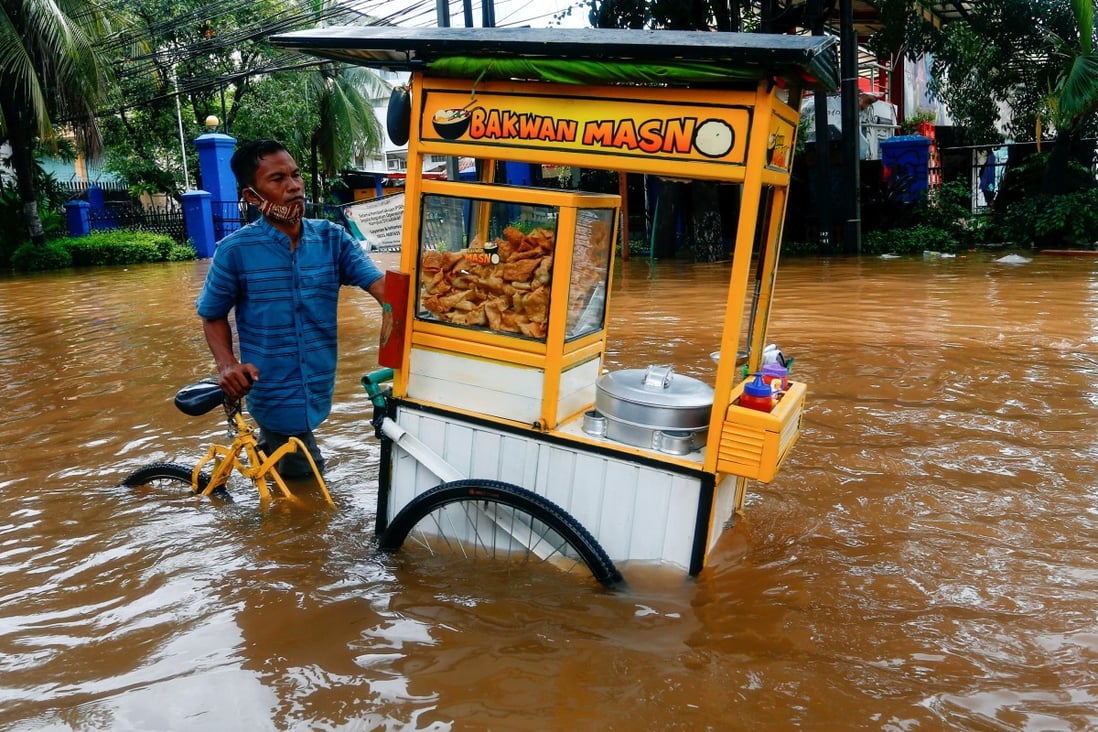 A street vendor pushes his cart through the water in an area affected by floods following heavy rains in Jakarta, Indonesia on Saturday. Photo: Reuters