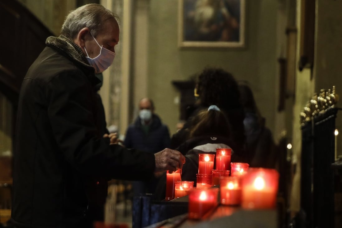 A man lights a candle during a Mass at the San Biagio church in Codogno, northern Italy on Sunday. Photo: AP