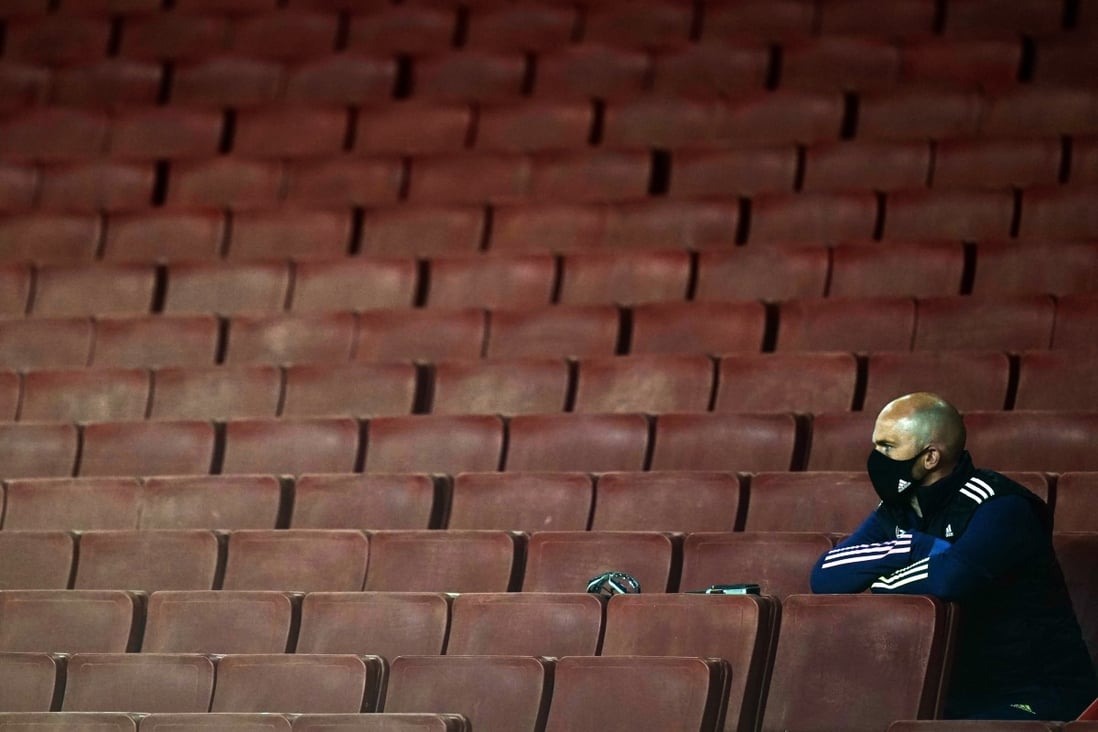 A stadium staff member wearing a protective face mask sits in the stands during an English Premier League match between Arsenal and West Ham United in London in September 2020. Photo: EPA