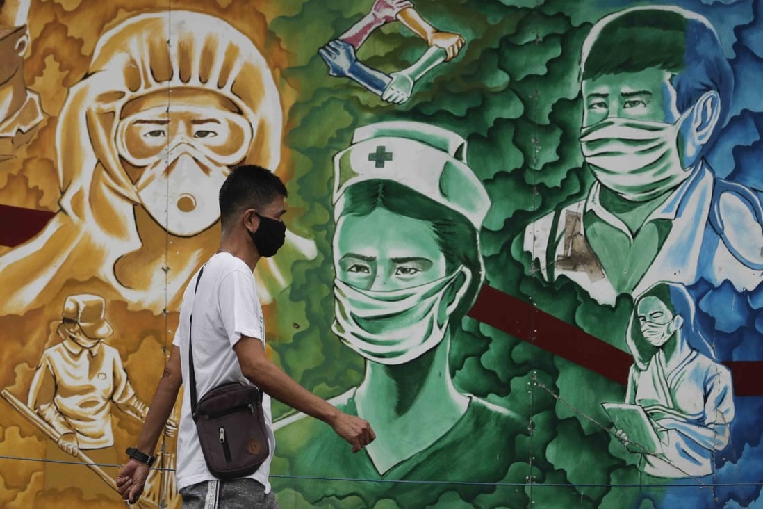 A man wearing a protective mask to prevent the spread of the coronavirus walks beside a mural of health workers outside the Mission Hospital in Pasig, Philippines on Monday. Photo: AP