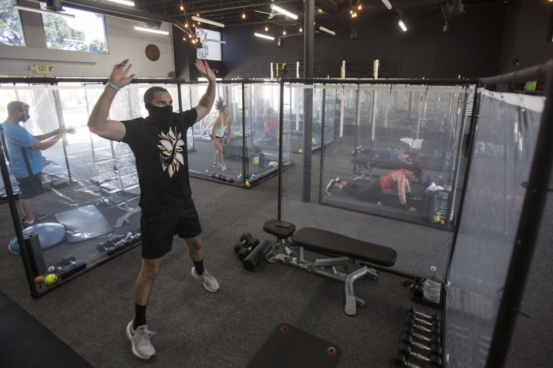 People exercise behind plastic sheets in their workout pods while observing social distancing at a gym in California. Photo: TNS