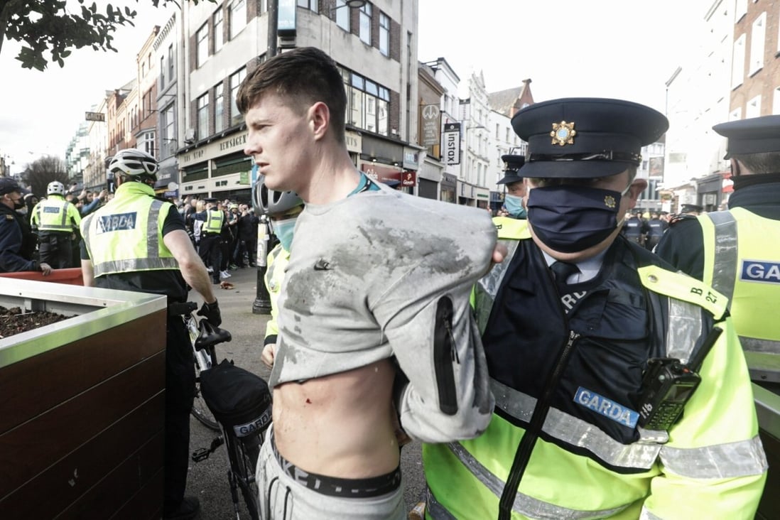 A police officer restrains a demonstrator during an anti-lockdown protest in Dublin city centre. Photo: PA / DPA