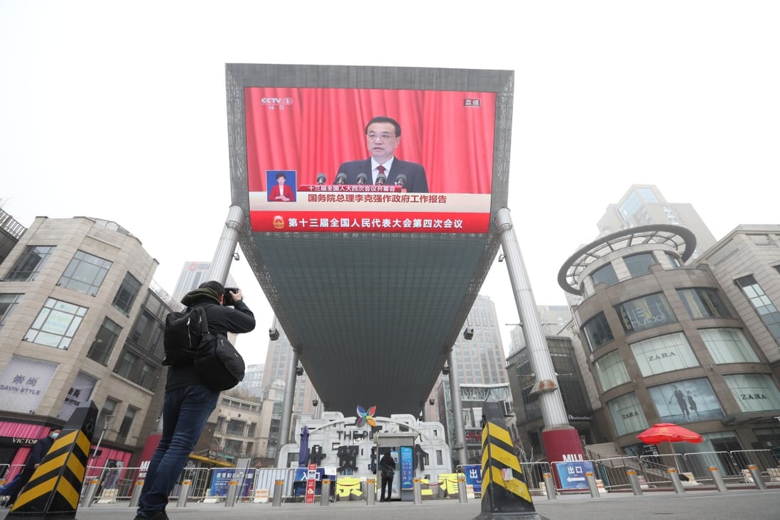 Chinese Premier Li Keqiang makes government report at the opening of NPC displayed in a big TV screen at a shopping area in Beijing on Friday morning, March 5, 2021. Photo: Simon Song