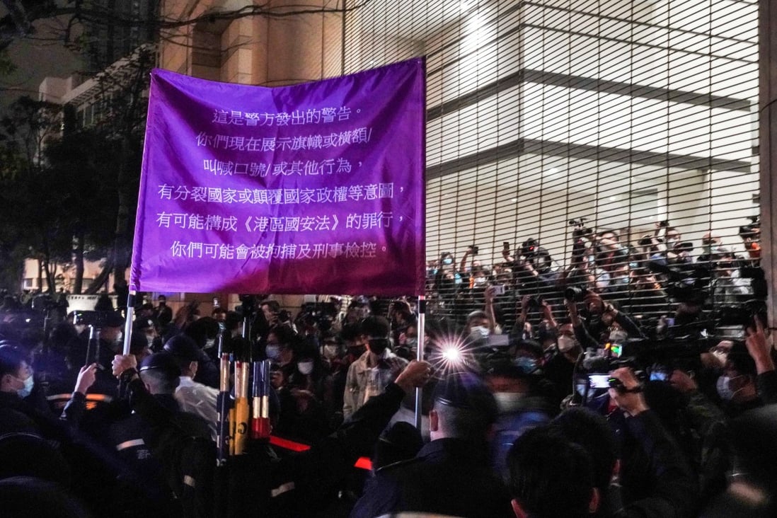 Police officers raise a warning flag against supporters of the 47 activists outside West Kowloon Court. Photo: Felix Wong