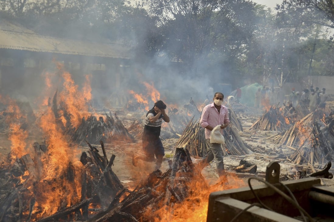 Relatives react to heat emitting from the multiple funeral pyres of COVID-19 victims at a crematorium in the outskirts of New Delhi, India, last month. Photo: AP