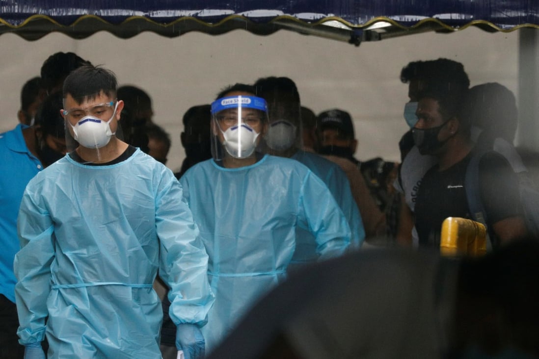 Personnel in protective gear usher a group of migrant workers onto a bus to a government quarantine facility after they tested positive for Covid-19 at Westlite Woodlands dormitory in Singapore. Photo: Reuters
