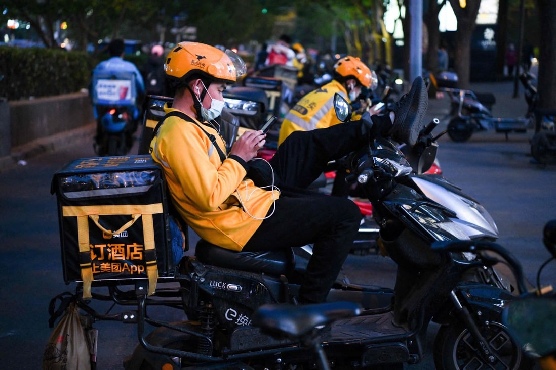 Meituan delivery riders rest on their electric scooters while waiting for orders outside a restaurant in Beijing on April 26, 2021. Photo: AFP