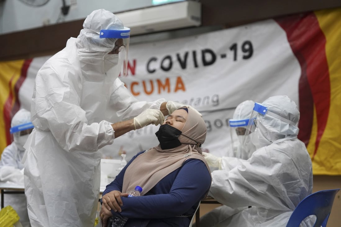 A medical worker collects a swab sample from a woman at a Covid-19 testing centre in Ulu Klang, Kuala Lumpur. Photo: AP