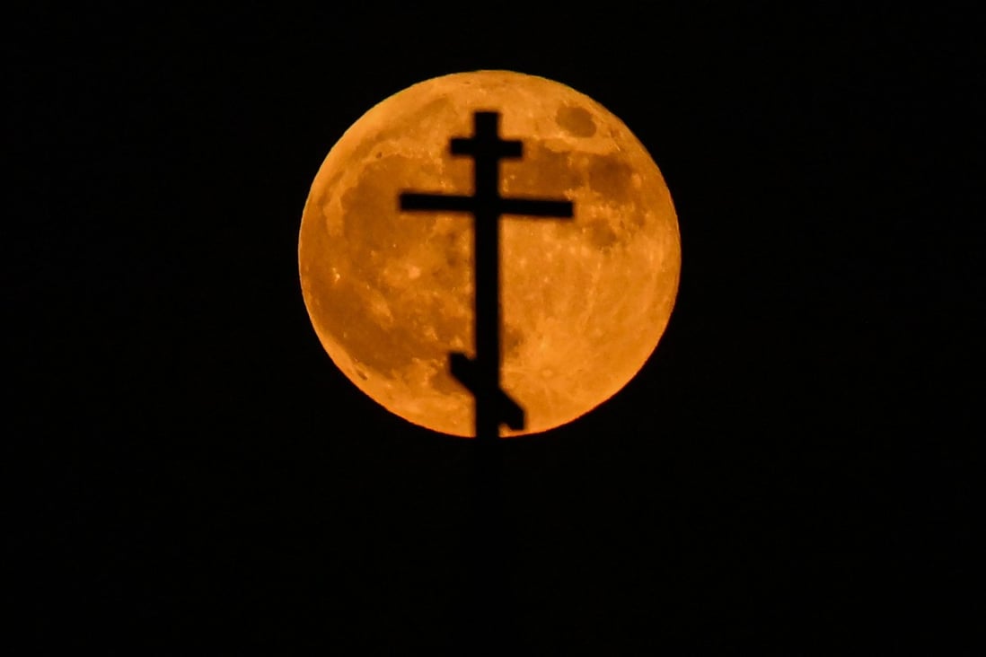 The super blood moon rises over the cross on top of an Orthodox church in the city of Rossosh, Russia on Wednesday. Photo: AFP