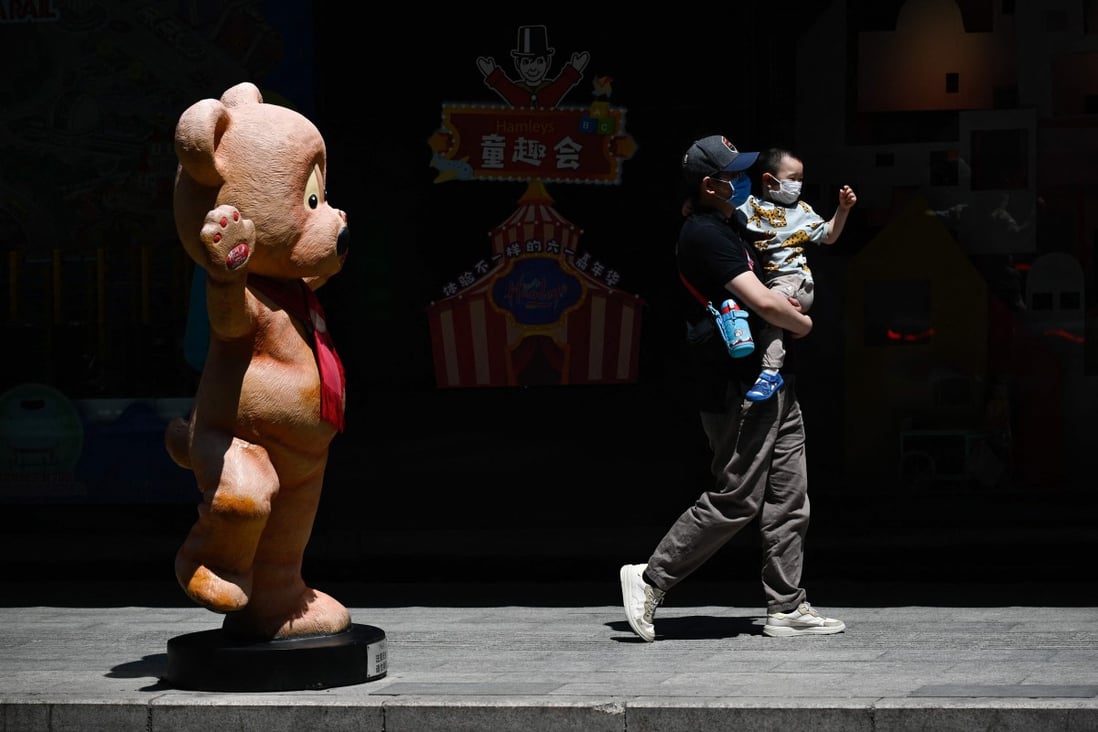 A man holding a child walks past a toy mall on International Children’s Day in Beijing on June 1. Photo: AFP