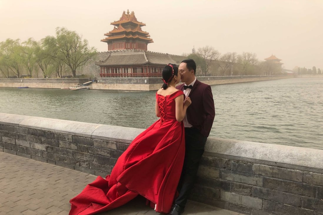 A couple poses for wedding photos near the Forbidden City amid a sandstorm in Beijing on March 28. While analysts say Chinese couples should be given more incentives to have three children, the environmental impact of an increase in the world’s population has not been factored in. Photo: AP