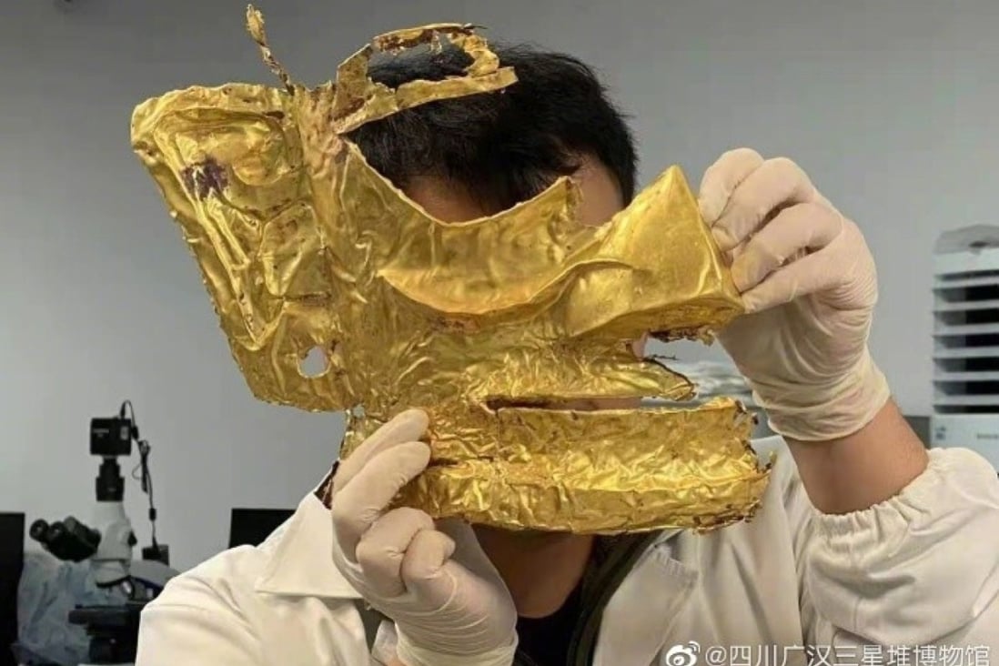 An archaeologist holds a newly excavated gold mask from the Sanxingdui site. Photo: Handout