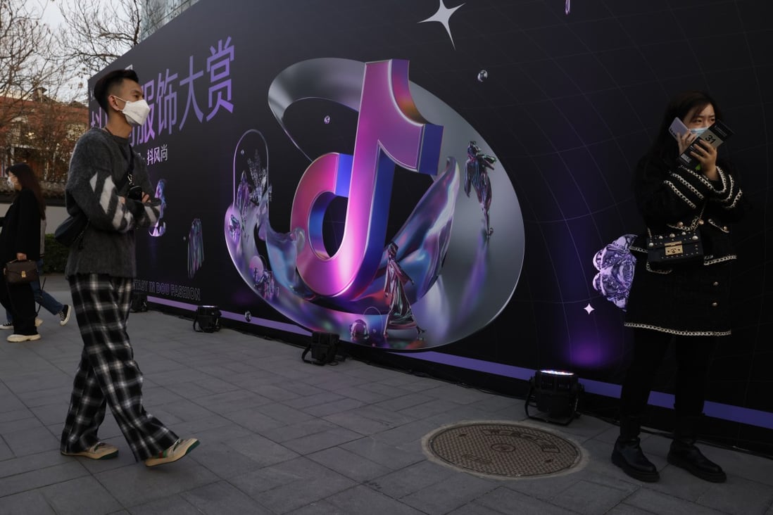 A woman speaks on her phone near the logo for Douyin, the Chinese version of TikTok, in Beijing on March 31. After Tencent’s vice-president compared personalised short videos to pig feed, ByteDance fired back on Friday, calling the comments stigmatising. Photo: AP