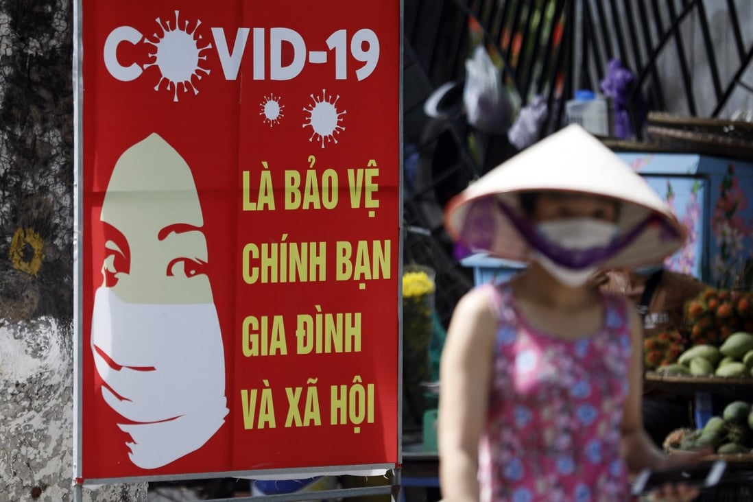 A woman walks past a sign bearing Covid-19 prevention advice in Hanoi. Photo: EPA-EFE