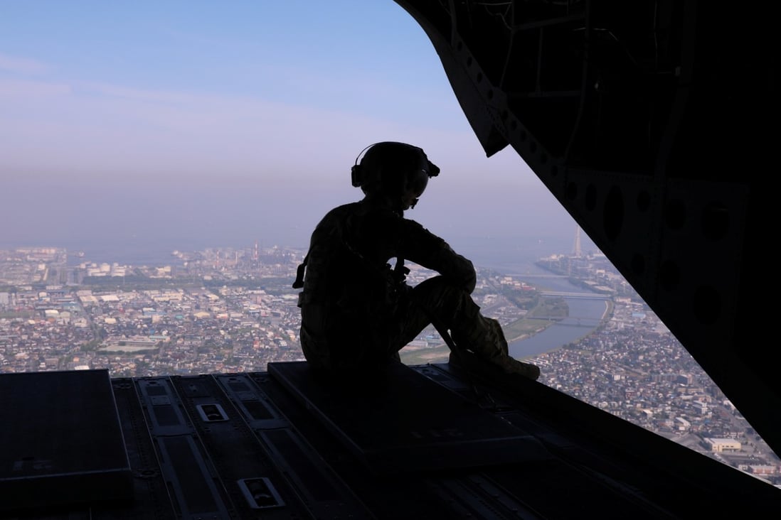 A US soldier looks out over Tokyo from the back of a military transport helicopter in 2019. Photo: Reuters