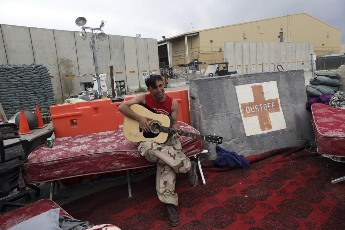 An Afghan soldier plays a guitar that was left behind after the American military departed Bagram airbase north of Kabul, Afghanistan. Photo: AP