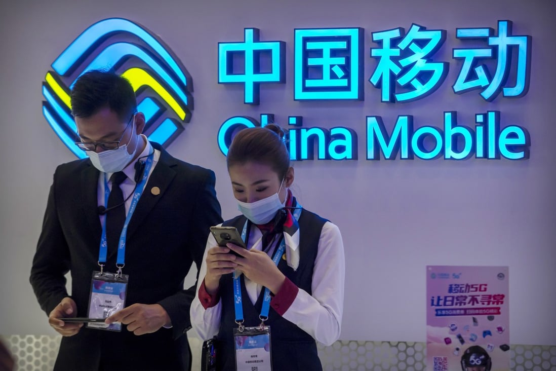 In this Oct. 14, 2020 file photo, staff members use their smartphones at a display from Chinese telecommunications firm China Mobile at the PT Expo in Beijing. Photo: AP