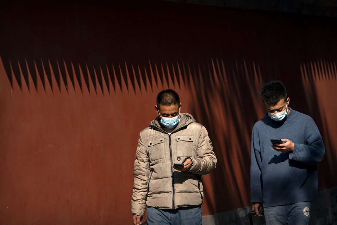 Two masked men on their smartphones at the Ditan Park in Beijing on Tuesday, February 9, 2021. Photo: AP
