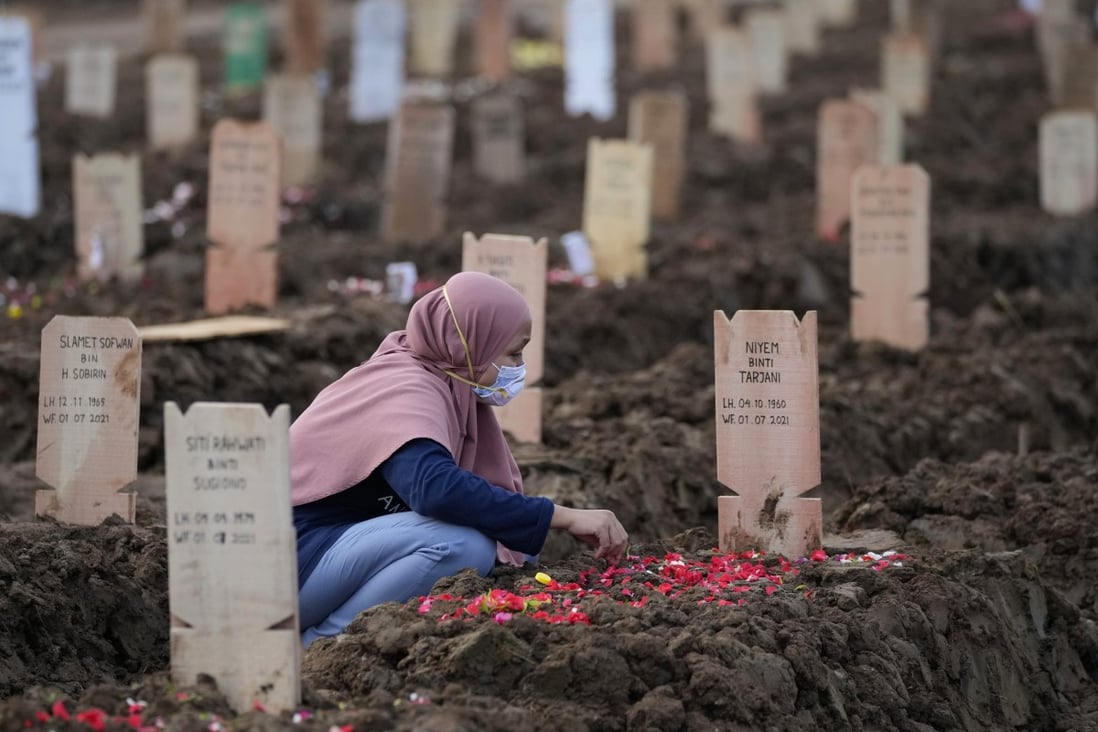 A woman sits by the grave of a relative who died of Covid-19 in Jakarta earlier this month. Photo: AP