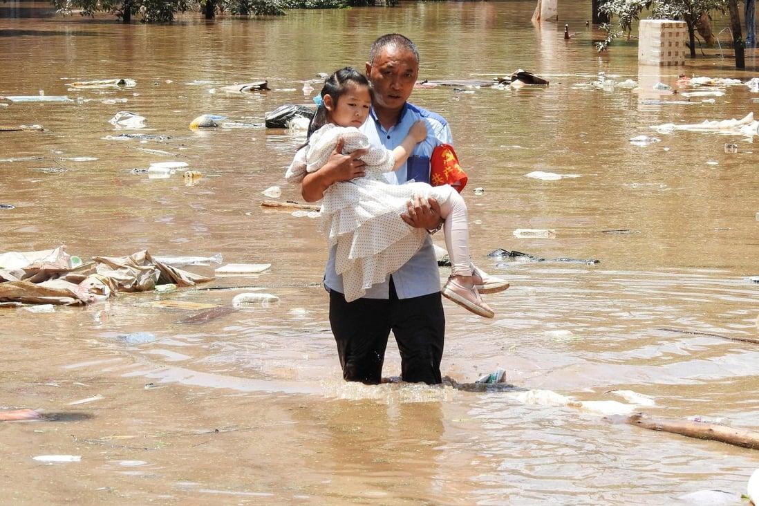A village official evacuates a child from a flooded area on Monday following heavy rains in Dazhou, Sichuan province. Photo: AFP