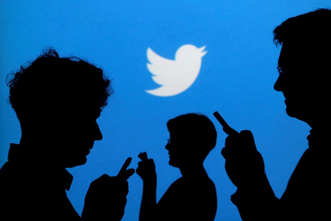 People holding mobile phones are silhouetted against a backdrop projected with the Twitter logo in this illustration picture taken in Warsaw on September 27, 2013. Photo: Reuters
