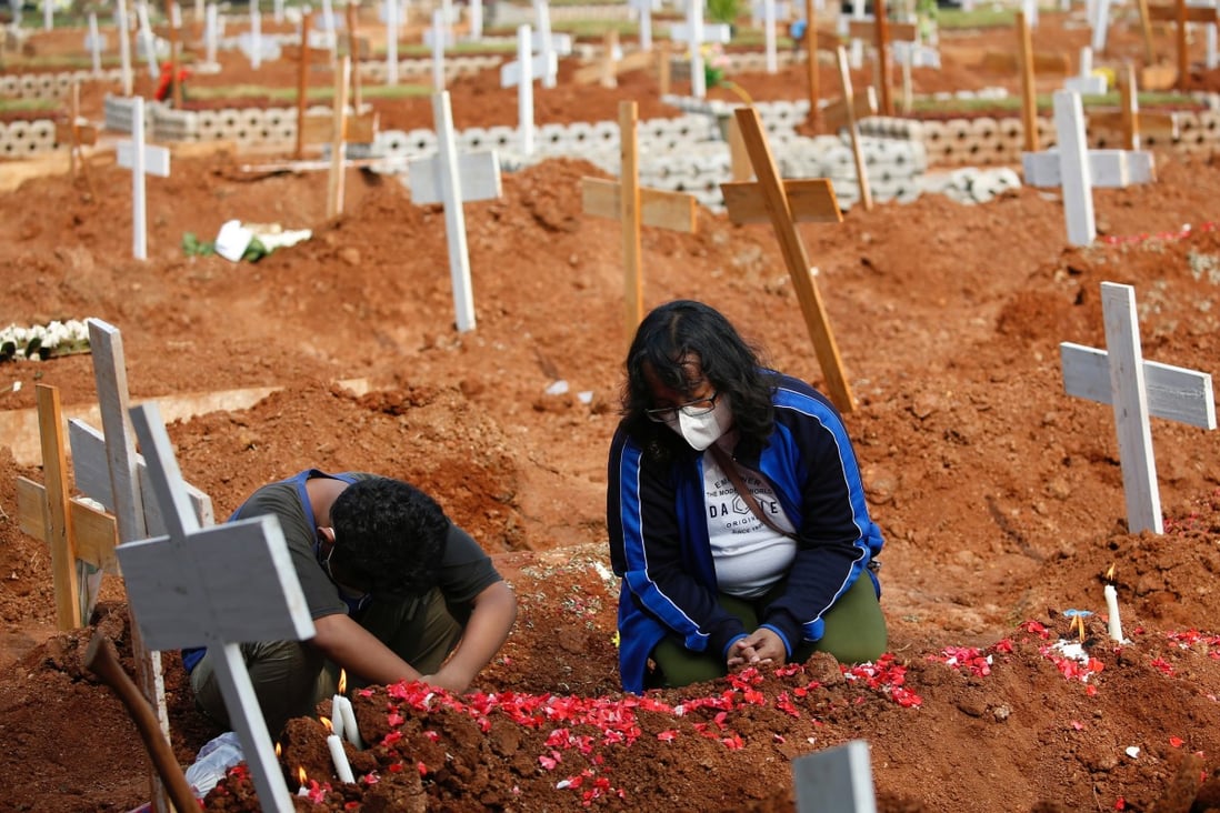 A woman and her son pray at the grave of their husband and father at a burial area provided by the government for Covid-19 victims on the outskirts of Jakarta, Indonesia. Photo: Reuters