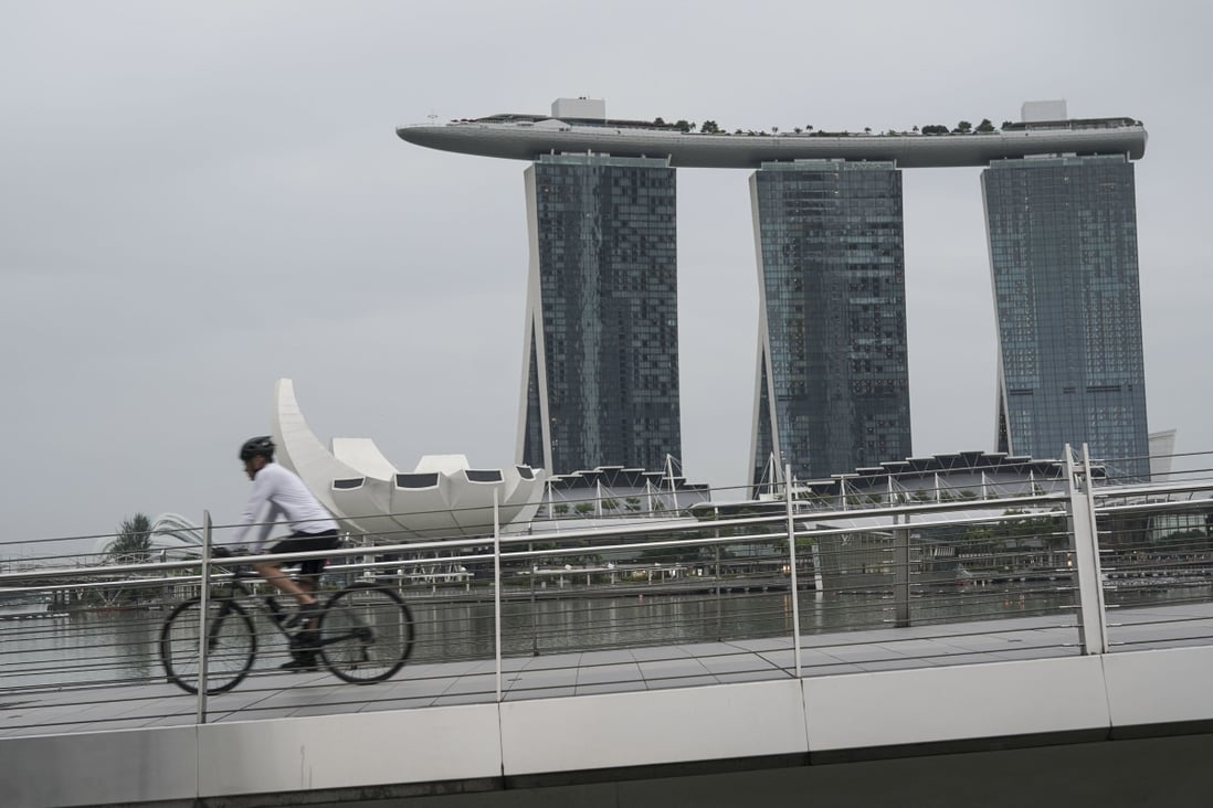 A man cycles along the Jubilee Bridge in front of the Marina Bay Sands in Singapore, which is experiencing a surge in coronavirus infections. Photo: EPA-EFE