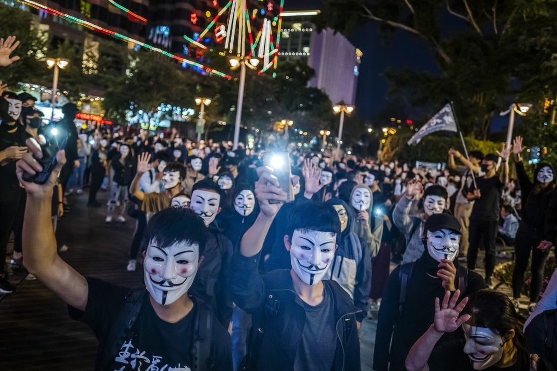 Mask-wearing protesters hold their smartphones aloft during a rally in the Tsim Sha Tsui district of Hong Kong in November 2019. Photo: Bloomberg
