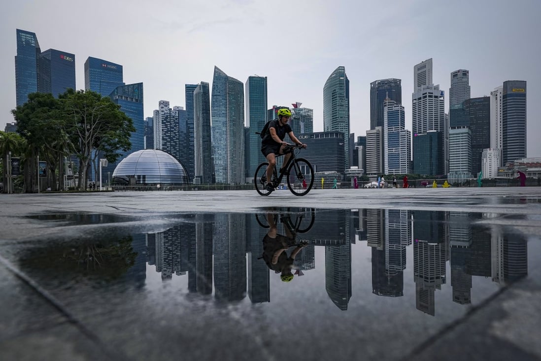 A cyclist reflected in a puddle rides past the skyline of Singapore’s financial district. A special purpose acquisition vehicle backed by Hong Kong billionaire Richard Li Tzar-kai is buying Singapore’s PropertyGuru, Southeast Asia’s biggest property technology company. Photo: EPA-EFE