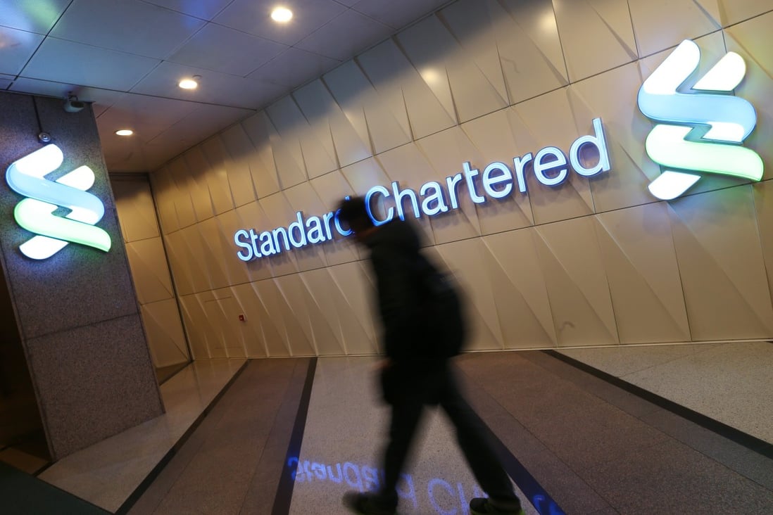 A man walks past a logo for Standard Chartered in Central. Photo: David Wong