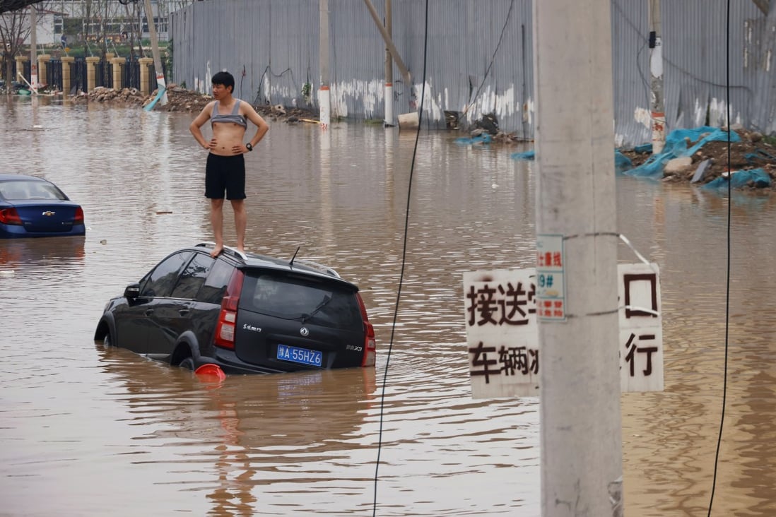 A man stands on a stranded vehicle on a flooded road following heavy rainfall in Zhengzhou, Henan province, China on July 22. Photo: Reuters