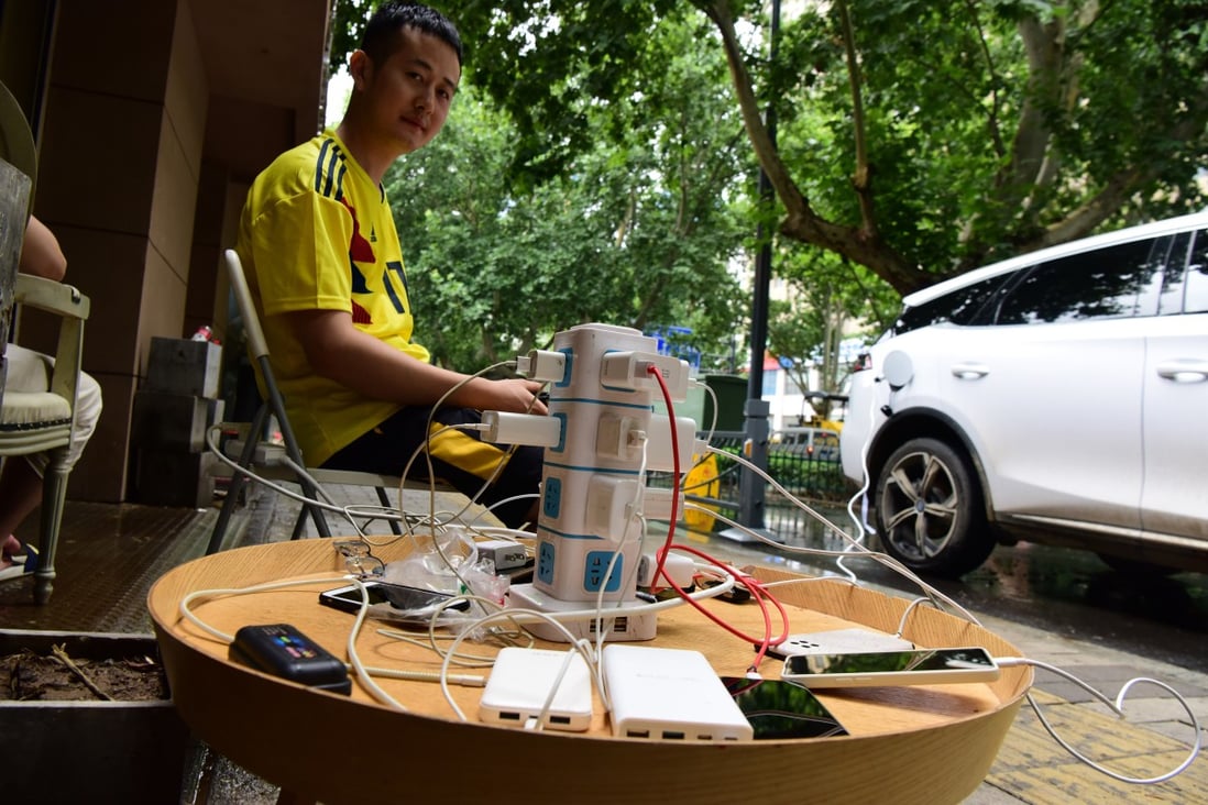 A local resident in Zhengzhou shares electricity from his electric car with people in need of power. Photo: Xinhua