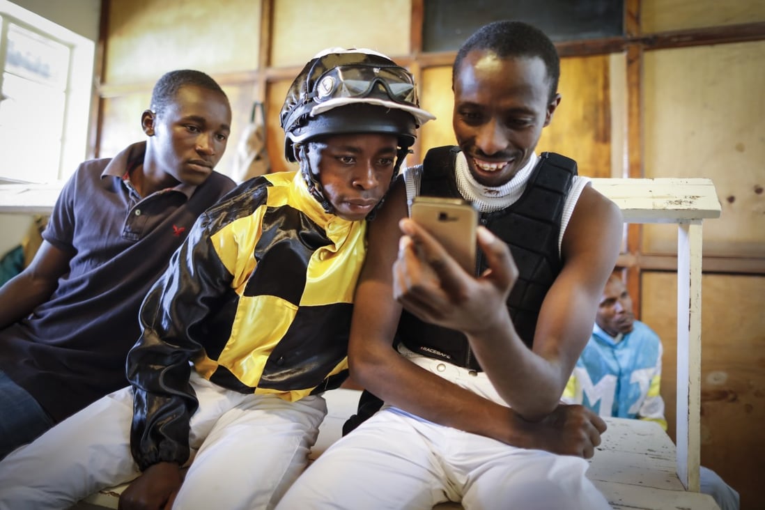 Jockeys watching their race on a mobile phone at the Ngong racecourse in Nairobi, on October 21, 2018. Photo: EPA-EFE.
