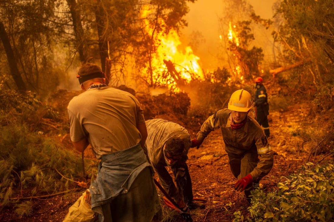 Firefighters and volunteers use a hosepipe to extinguish a fire in the village of Glatsona on Evia island on Monday. Photo: AFP