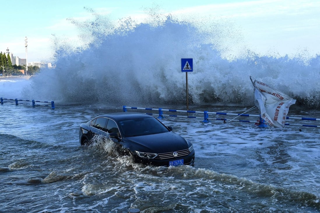A car sitting in flood waters as waves caused by Typhoon In-Fa surge over a barrier along the coast in the Shandong provincial city of Qingdao in eastern China on July 25, 2021. Photo: AFP