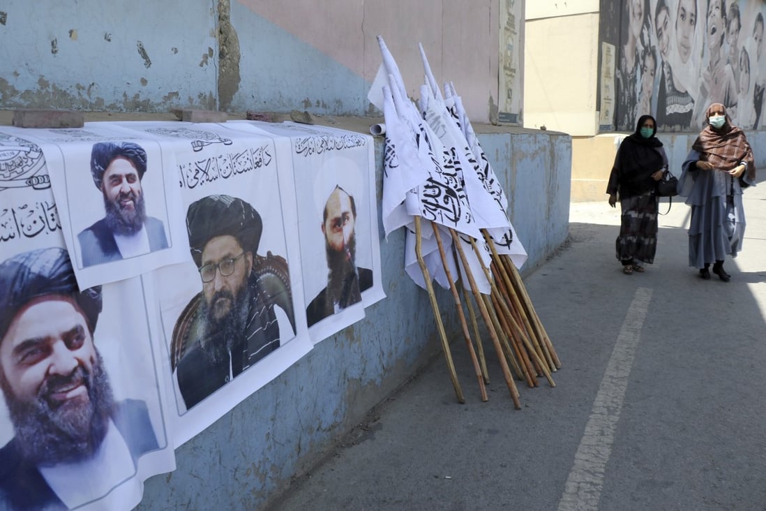 Afghan women walk by posters of Taliban leaders and flags in Kabul, Afghanistan, on August 25. Photo: AP