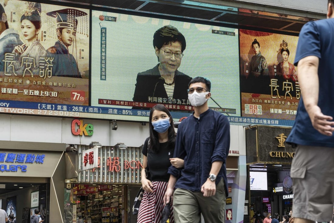 Pedestrians walk past a screen showing a news conference featuring Hong Kong leader Carrie Lam. Photo: Agency