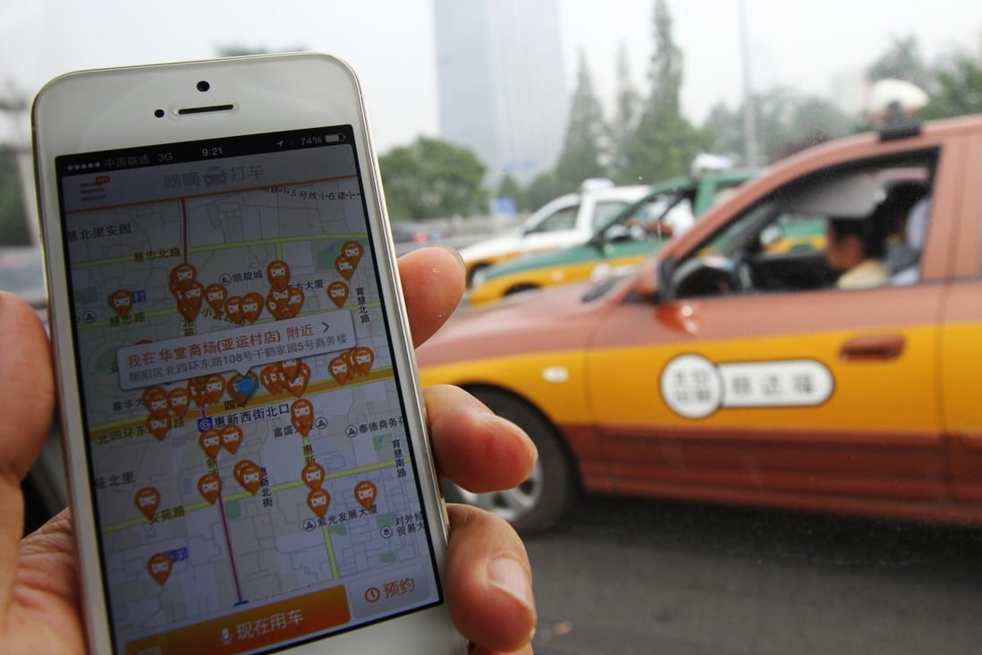 A smartphone showing the application of Didi Dache, with a taxi passing by in Beijing on 19 June 2014. The company merged with Kuaidi Dache to become Didi-Chuxing in 2015. Photo: Simon Song
