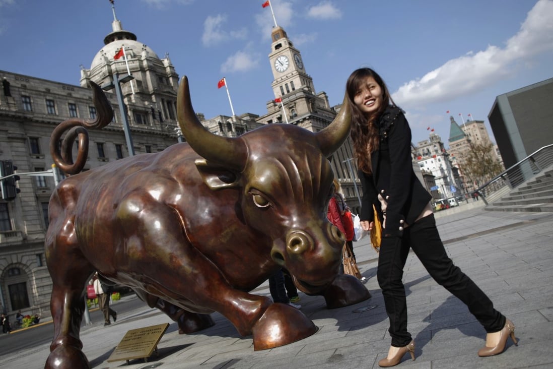 A woman poses next to a bull statue known as the Bund Financial Bull along the Huangpu River in Shanghai. Photo: Reuters