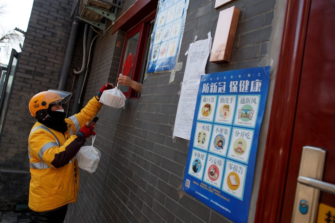 A delivery driver picks up takeaway food that is handed through the window of a restaurant in Beijing in March 2020. Photo: Reuters