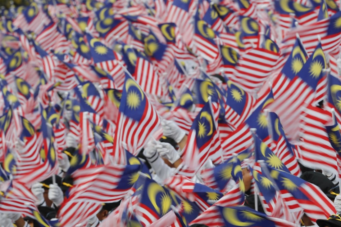 Students wave national flags during Independence Day celebrations in Malaysia. Photo: AP