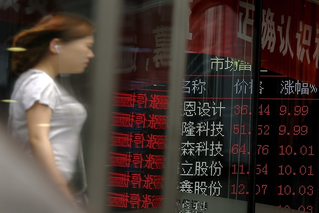 A woman is reflected on a glass panel as she walks by a brokerage house in Beijing. Regulatory risks hit Macau casino stocks this week while the economy loses further momentum. Photo: AP